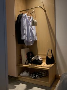 an open closet with clothes and handbags hanging on the rack, next to a pair of shoes