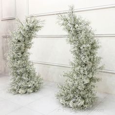 two tall white vases sitting next to each other on a tile floor in front of a wall