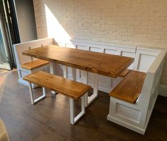 a wooden table and bench in front of a brick wall with white wainscothes