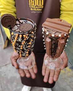 two people holding glasses with chocolate and oreo cookies on them, one is holding an ice cream sundae