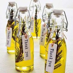 four bottles filled with yellow liquid and herbs