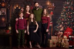 a family poses in front of a christmas tree