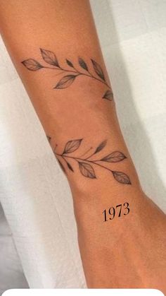 a wrist tattoo with leaves on it