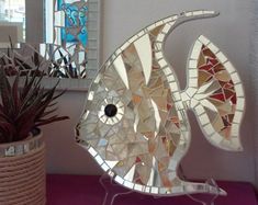 a fish shaped mirror sitting on top of a table next to a potted plant