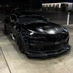 a black camaro is parked on the street at night