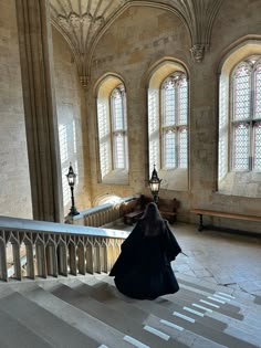 a woman is sitting on the stairs in an old building with stained glass windows and chandeliers