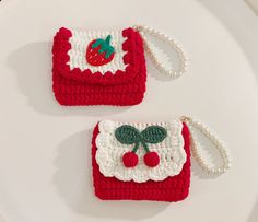 two red and white crocheted purses sitting on top of a white plate