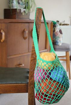 a green netted bag sitting on top of a wooden chair