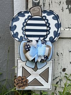 a blue and white mickey mouse door hanger with a bow on it's head