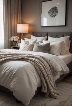 a bed with white comforter and pillows in a bedroom next to a large window