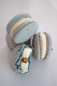 three macaroons with white and blue frosting on them, one broken in half