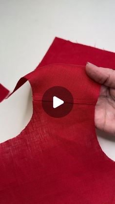 someone is making a red piece of fabric with the cut off part on top of it