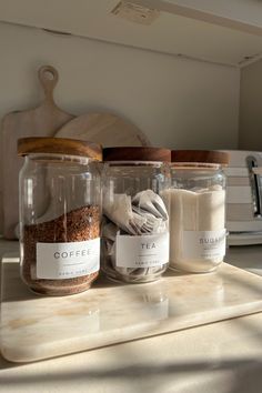 three jars filled with different types of spices on a counter top next to a cutting board