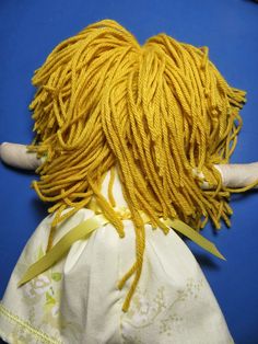 a doll with yellow dreadlocks on it's head sitting on a blue surface