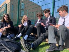 four young people sitting on benches in front of a fence