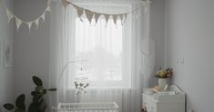 a baby's room with a crib, dresser and window