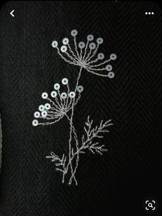 a close up of a flower on a black cloth with white thread and small beads