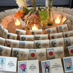 there are many cards that have been placed on the table with candles and flowers in them