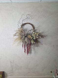 a wall mounted wreath with dried flowers on it