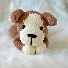 a crocheted dog is laying down on a white fur covered surface with it's eyes open