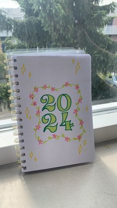 a spiral notebook with the number twenty nine on it sitting next to a window sill