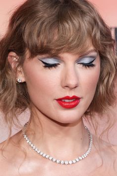 taylor swift wearing red lipstick and blue eyeshadow with diamond necklace on her neck