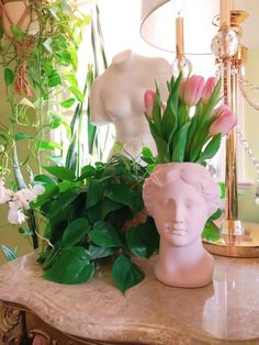 a vase with pink flowers and greenery on a table