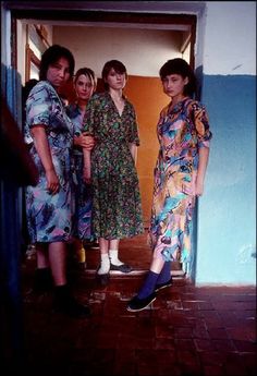 three women standing next to each other in front of a door with their feet on the ground