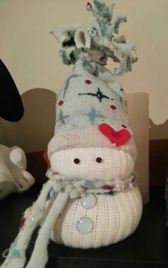 a knitted snowman sitting on top of a table next to a stuffed animal