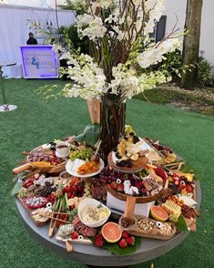 a table topped with lots of food on top of a lush green field