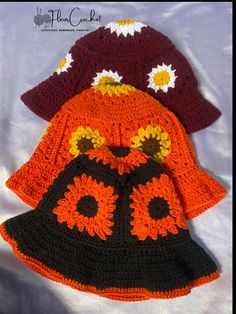 three crocheted hats are on top of each other, one is orange and the other is black