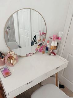 a white desk with a mirror, phone and other items on it