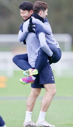 two young men are playing with each other on the soccer field while one man is carrying another