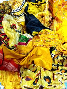 a pile of yellow and blue cloths laying on top of each other in different colors