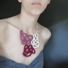 a woman wearing a purple and white necklace with two hearts attached to the neckline