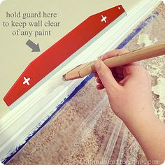 a hand holding a paint roller and pointing at the wall with an arrow painted on it