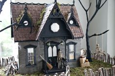 a doll house with decorations on the roof and in front of it is a skeleton holding a broom