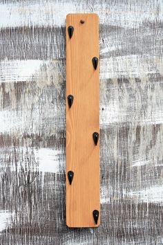 a piece of wood that has some black nails on it and is hanging from the side