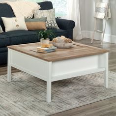 a living room with a blue couch, coffee table and pillows on the rugs