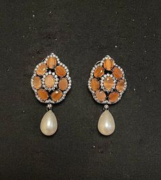 PUNJABI BRIDAL JEWELRY - WOMEN'S TRADITIONAL ORANGE ONYX & PEARL DROP EARRING Elegant set of earrings with beautiful orange onyx & CZ mini crystal. A versatile pair of earrings with orange onyx & Pearl drop. The engraved silver plated earring of traditional design adds an artisanal touch to the earrings. Details: Handcrafted Jewelry Metal: Metal Alloy, Silver Plated Stone:  Orange Onyx, CZ Crystal & Pearl Drop Style: Contemporary yet Traditional Closure:  Push back clasp B Anu Designs jewelry pi Orange Pear-shaped Jewelry, Orange Drop Earrings For Anniversary, Orange Teardrop Jewelry For Formal Occasions, Orange Drop Earrings For Formal Occasions, Orange Teardrop Sterling Silver Earrings, Elegant Orange Sterling Silver Earrings, Orange Dangle Earrings For Formal Occasions, Handmade Orange Earrings For Formal Occasions, Elegant Orange Drop Earrings