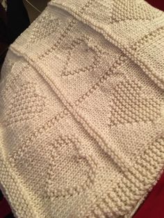 a white knitted blanket sitting on top of a bed