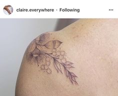 the back of a woman's shoulder with flowers and leaves tattooed on her arm