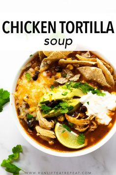 chicken tortilla soup in a white bowl topped with sour cream and cilantro