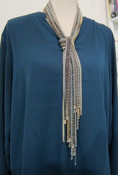 a mannequin wearing a blue shirt with silver chains on it's neck