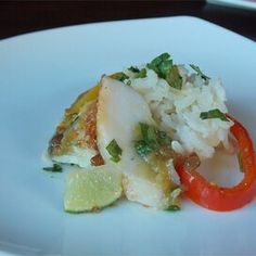 a white plate topped with rice and vegetables on top of a wooden table next to a red pepper