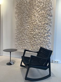 a chair and table in front of a wall sculpture