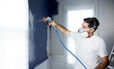 a man is painting the walls in his house with blue paint and white rollers