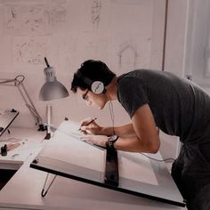 a young man is writing in his notebook while listening to headphones and holding a pen