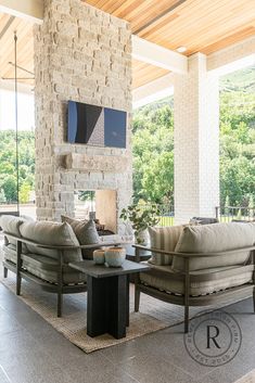 a living room with two couches and a fireplace in the center, surrounded by stone walls