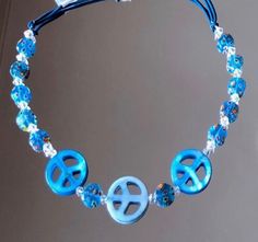 "This beaded jewelry versatile headband is made with blue peace signs with flowered millefiori glass beads & precious crystal throughout.  This one size fits all assembly is patented and allows the headband to be worn as a necklace. Perfect for that young girl who loves to sparkle!  18\" Long and stretches to fit comfortably on head.  Lobster clasps are stainless steel." Adjustable Blue Hippie Necklace, Adjustable Peace Sign Necklace, Adjustable Peace Sign Necklace As Gift, Adjustable Round Necklace With Czech Glass, Hippie Blue Beaded Necklace With Round Beads, Blue Hippie Beaded Necklace For Gift, Adjustable Round Hippie Jewelry, Adjustable Blue Spiritual Beaded Necklace, Spiritual Blue Adjustable Beaded Necklace